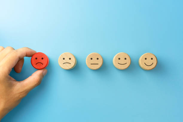 istock The client's hand picked the sad face icon on wooden cube on blue background, Customer service evaluation and satisfaction survey concepts 1282488434