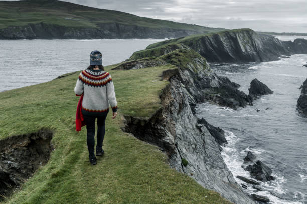 A woman in an Icelandic sweater is walking on an autumn day on St Ninian Island in the Shetland Islands.