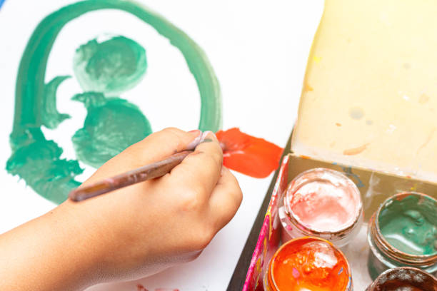 istock Small kid drawing with brush and paint. Childhood education concept. 1282490837