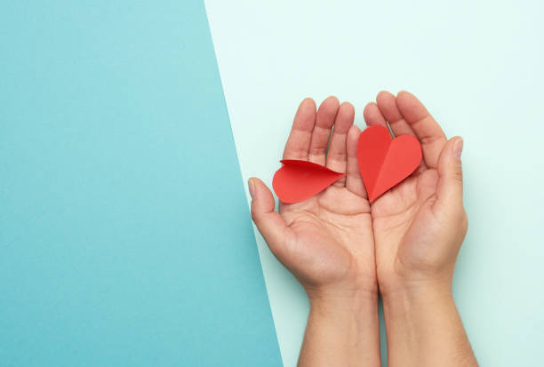 istock female hand holding red paper hearts on a blue background 1282493447