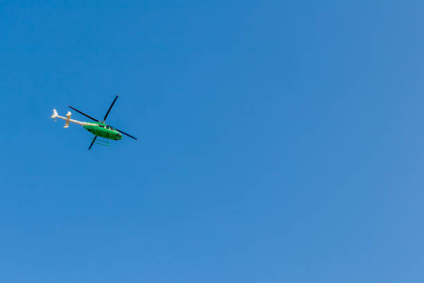 A view from below, green helicopters flying in the sky during the day time.