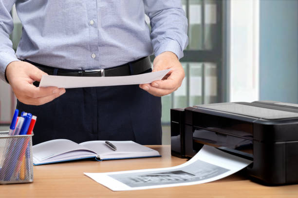 istock Businessman working on financial analytics and marketing sales strategy in office. Process of the print of documents on the printer. 1282496383