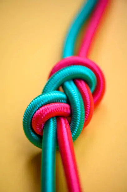 Two different colored ropes tied together with yellow background.