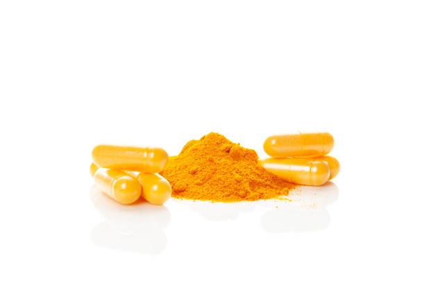 istock Turmeric (curcumin) powder heap and capsules isolated on white. 1282499271
