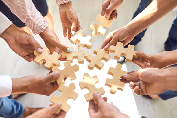 employés d’entreprise jouant au jeu et joignant des morceaux de puzzle pendant l’activité de renforcement d’équipe - partnership cooperation teamwork puzzle photos et images de collection