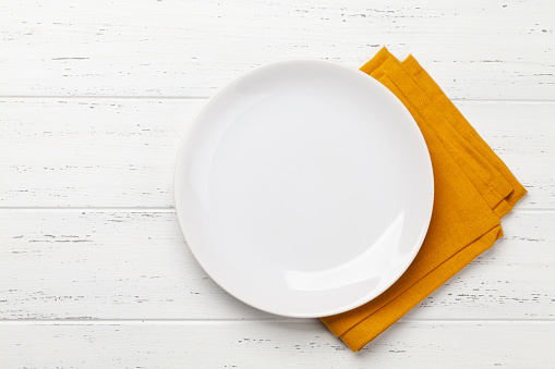 White empty plate and napkin on wooden table. Top view flat lay with space for your meal