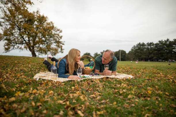 зрелая пара веселится на пикнике на природе - glasses grass women lying on front стоковые фото и изображения