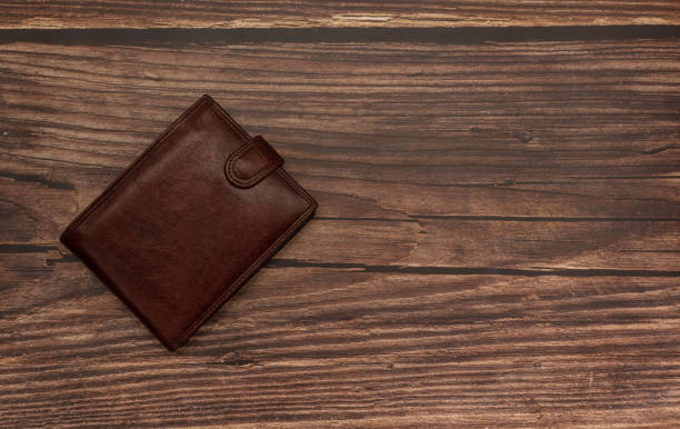 istock Closed brown wallet on wooden brown background 1282508173