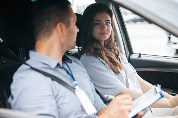 istock Male instructor praises attractive female student for driving successfully. Man writing something in paper and talking with pretty woman looking at him with respect. 1282510826