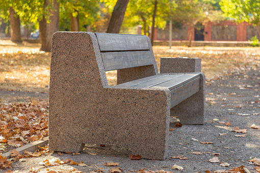 Stone and wooden bench in the autumn park