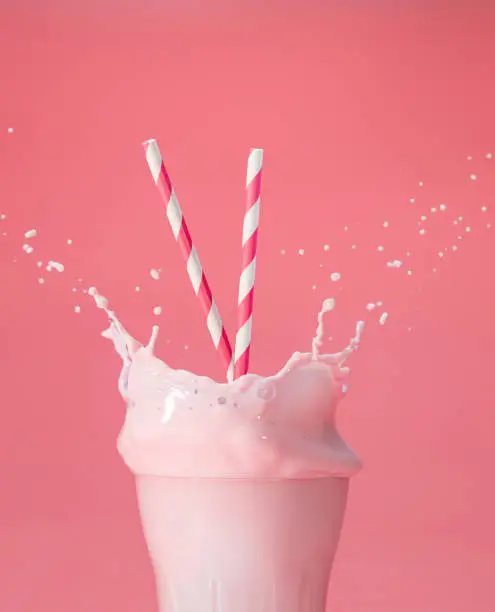 Photo of splashing berry milkshake on pink backdrop