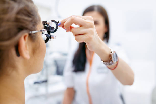 Female eye doctor testing patient's eyesight with phoropter