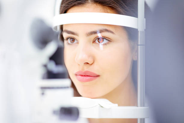 istock Young woman leaning with her face on optical instrument for eye exam 1282515073