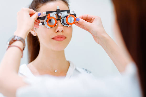 Female patient wearing phoropter, female doctor changing lenses to determine diopter