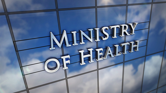 Ministry of Health on glass building. Mirrored sky and city modern facade. Healthcare, government, epidemic, virus, prevention and medical concept 3D rendering illustration.