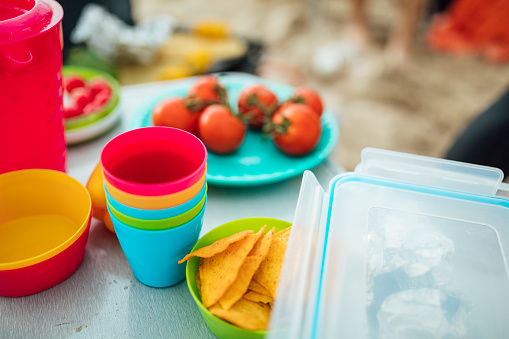 A table full of snacks presented in colourful camping shatterproof plastic bowls.