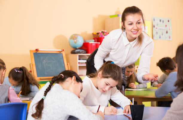 istock Teacher helping children drawing 1282518235
