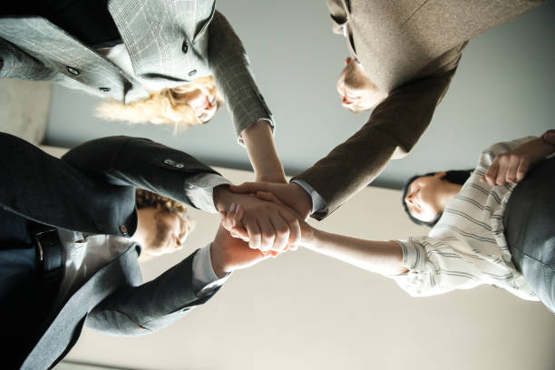 istock Four office workers are putting their hands together. United team conept. 1282520069