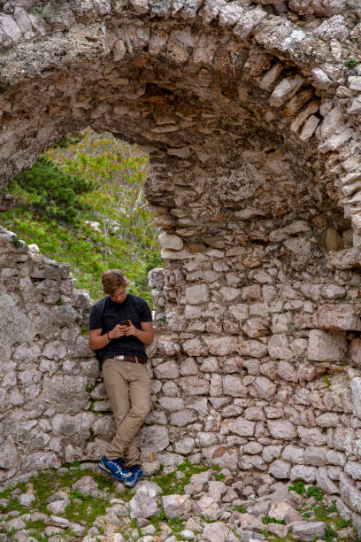 istock Young man uses phone under ancient archway 1282520365