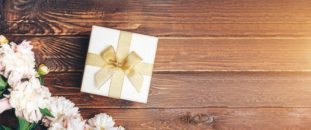 istock Beautiful delicate peonies and a white gift box with a bow on a wood background, blooming flowers, March 8, Mom s day, birthday present 1282529173