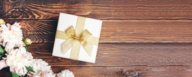 istock Beautiful delicate peonies and a white gift box with a bow on a wood background, blooming flowers, March 8, Mom s day, birthday present 1282529177