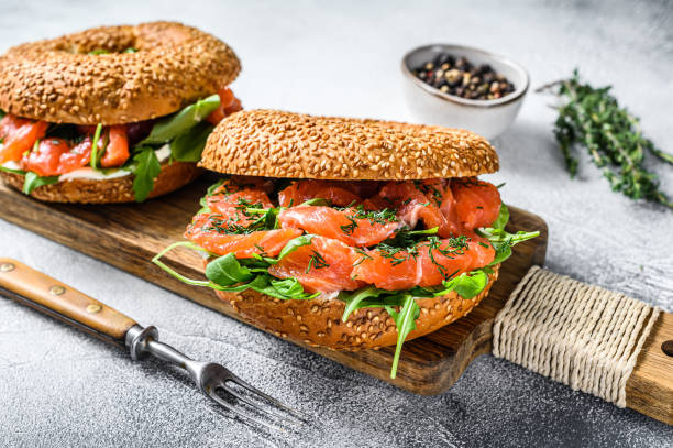 istock Smoked salmon bagels sandwich with soft cheese and arugula on a cutting board. White background. Top view 1282529364