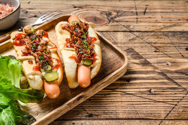 Hot dogs with fried bacon, onion and pickled cucumbers. wooden background. Top view. Copy space Hot dogs with fried bacon, onion and pickled cucumbers. wooden background. Top view. Copy space. Relish stock pictures, royalty-free photos & images