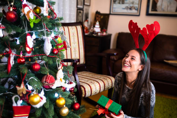 istock A happy young woman holding a present under the Christmas tree 1282532468