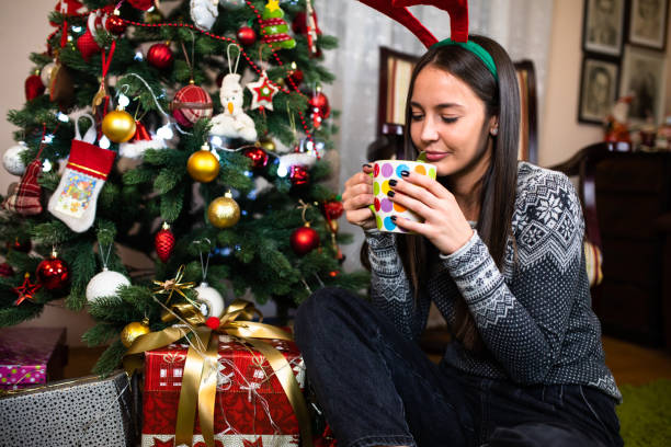 istock A pretty young woman having tea under a Christmas tree 1282532475