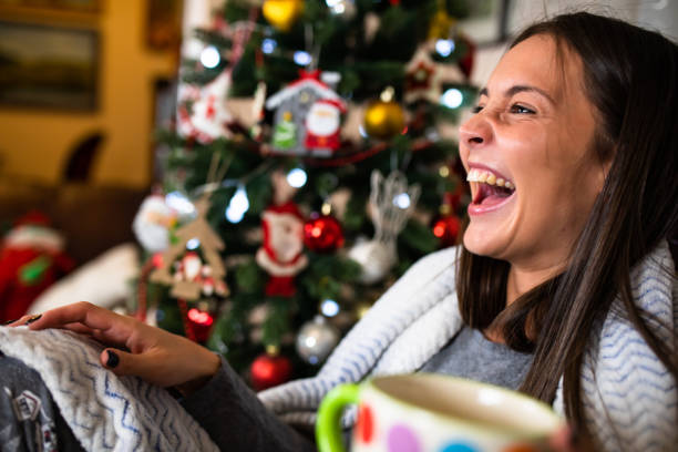 istock A pretty young woman laughing next to a Christmas tree 1282532488