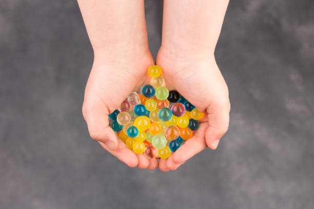 Water multiclooured gel balls. Child palms with hydrogel balls - orbeez.