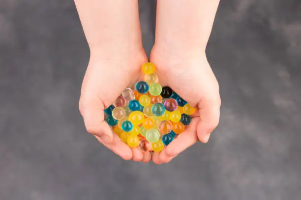 Water multiclooured gel balls. Child palms with hydrogel balls - orbeez. Polymer gel. Silica gel.