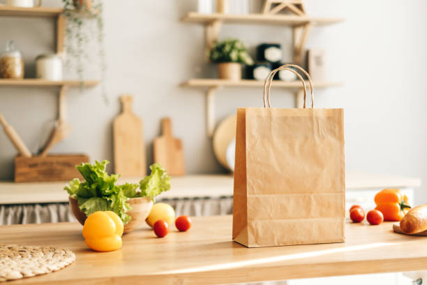 istock Eco shopping paper bag with fresh vegetables and baguette on table in kitchen 1282538534