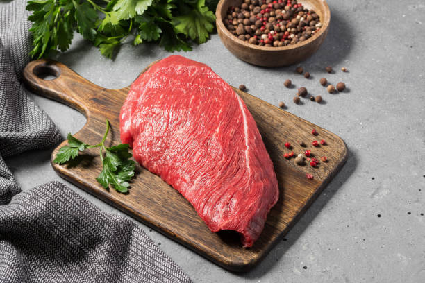 istock Raw beef meat on a wooden Board on a gray kitchen table 1282538595