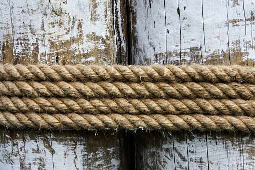 Four layers of rope tied around a old wooden log, in the shade on a sunny day