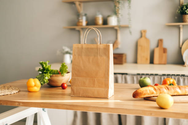 istock Eco shopping paper bag with fresh vegetables and baguette on table in kitchen 1282541233