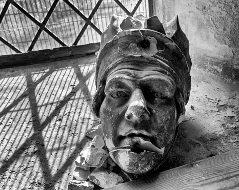 A broken medieval sculpture, probably a corbel, resting on the inside windowsill of the Church of St Mary the Virgin in Sedgeford, Norfolk, Eastern England, on a sunny day. (Added grain.)