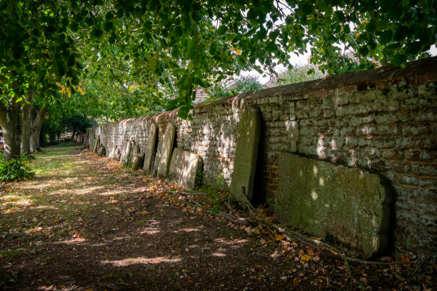 istock Old gravestones standing against a churchyard wall 1282542635