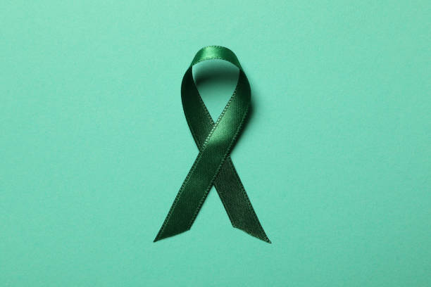 istock Green awareness ribbon on green background, top view 1282542894