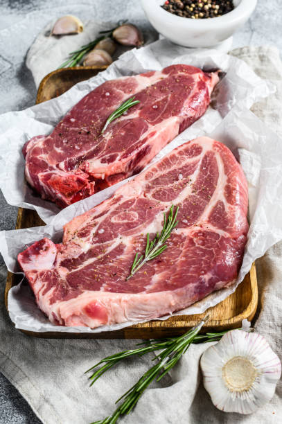 istock Raw pork steak on the bone. Marbled farm meat. Gray background. Top view 1282546864