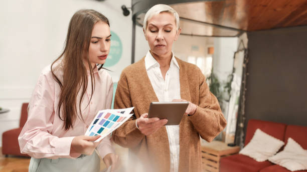 istock A white mature well-dressed ladyboss holding a tablet giving instructions to a young white fashionably dressed lady 1282546949