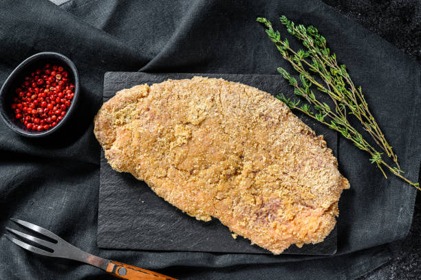 weiner schnitzel tedesco impanato fatto in casa.  sfondo nero. vista dall'alto - weiner schnitzel foto e immagini stock