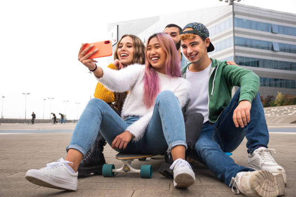 Happy group of friends takes a selfie outdoor. happy group of young skater friends takes a selfie sitting outdoors on a skateboard. adolescents hanging out stock pictures, royalty-free photos & images