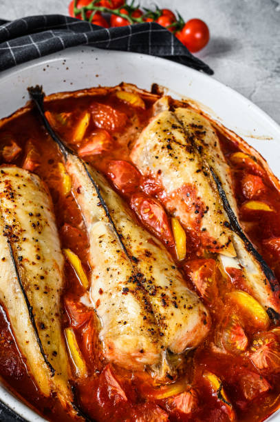 istock Cooking in tomatoes monkfish fish in a baking dish. Fresh seafood. Gray background. Top view 1282549008