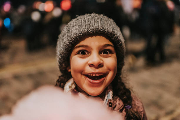 Stock photo of little girl having a cotton candy outside. She is visiting a public event during a winter day in London, UK. This file has a signed model release.