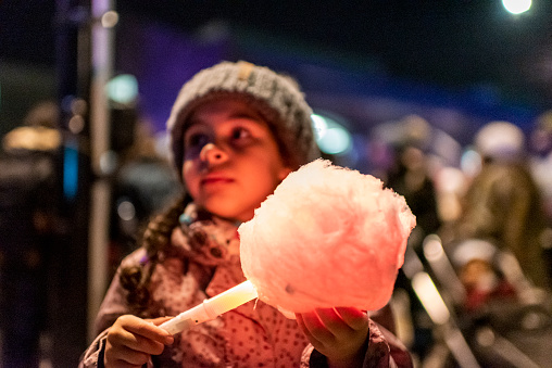 Stock photo of a little girl having a cotton candy outside. She is visiting a public event during a winter day in London, UK. This file has a signed model release.