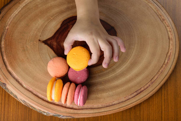 Macaroons, French traditional sweet. One of the ingredients in your recipe is almond flour. Child's hand showing that they are irresistible.