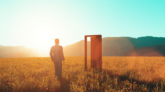 Man stands in front of an open door on a field. Sun sets in the horizon. Concept of making a right decision and move in the right direction, when an oppertunity unfolds.
Note: Digitally generated image.