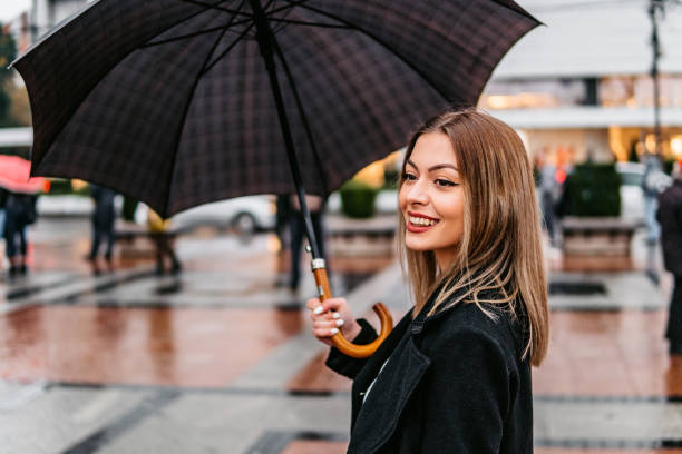 Young adult woman bouncing with umbrella in rainy weather, black and white photo