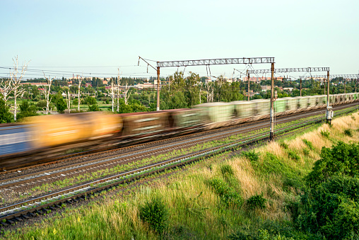 Train with different freight cars that are blurred at high speed on the background of the railway